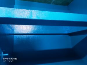 خزان مياه أرضي خرساني كبير يقوم داخله فريق عمل متخصص بعزل الجدران بمادة الإيبوكسي الأزرق مع تنفيذ أعمال تنظيف وصيانة خزانات المياه في جدة